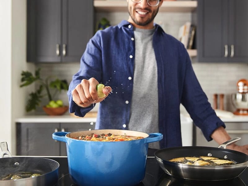 Person squeezing a lime into a pot of soup