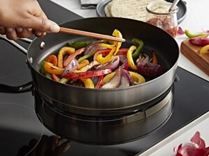 Person cooking bell peppers on an induction cooktop