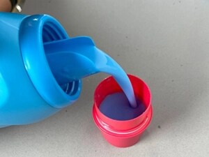 Bottle pouring fabric softener into a red cap
