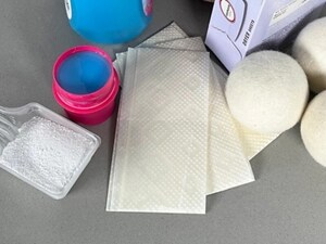 Close-up of wool dryer balls, fabric softener, detergent and dryer sheets
