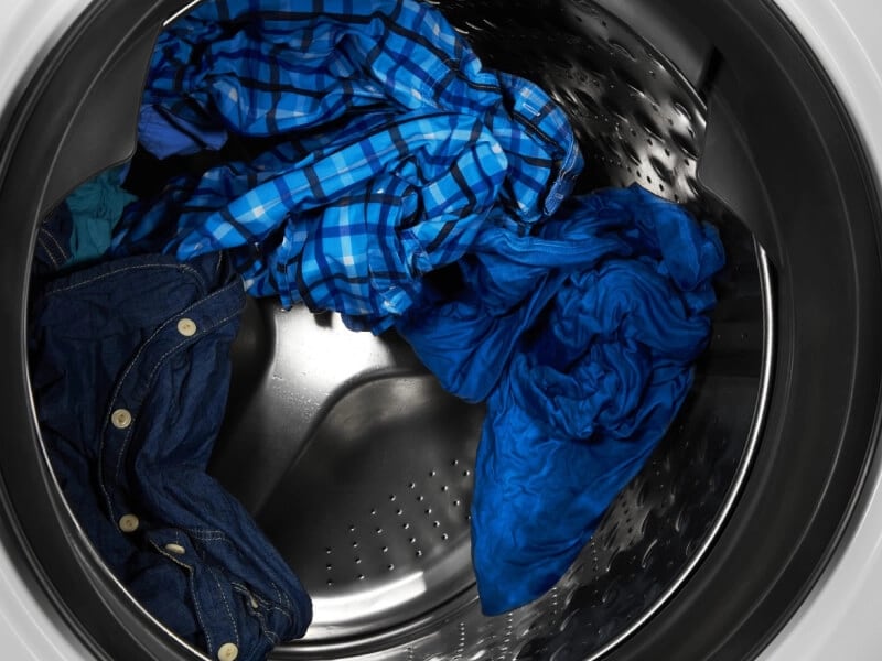 Wet, blue clothes inside of a washer drum