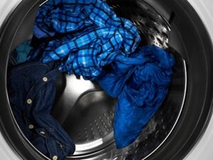 Wet, blue clothes inside of a washer drum