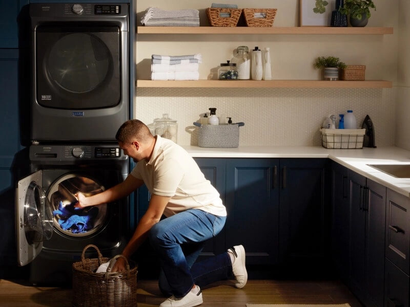 A man moving clothes from his Maytag® washing machine to a basket
