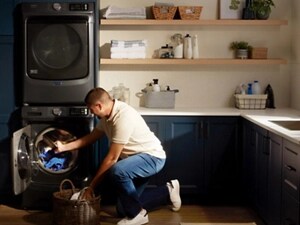 A man moving clothes from his Maytag® washing machine to a basket