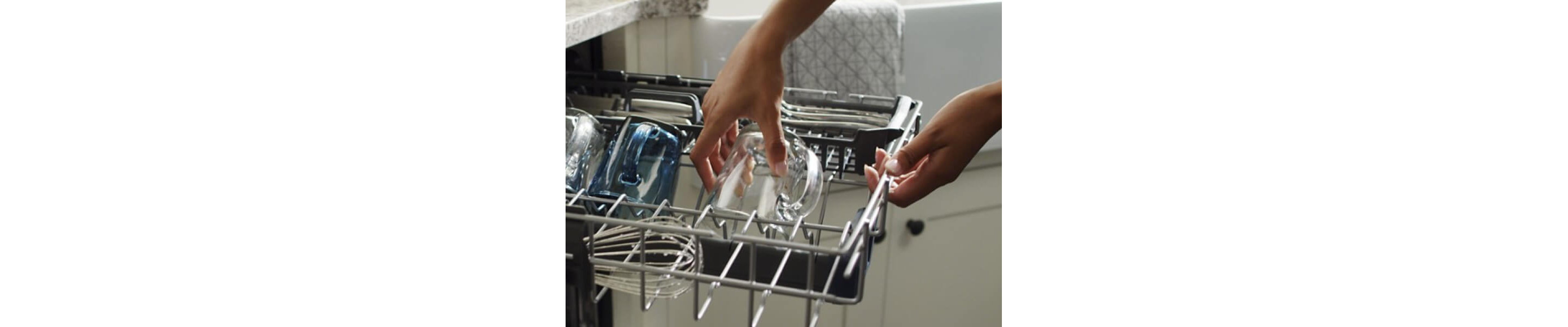 A person grabbing a glass mug out of a Maytag® dishwasher