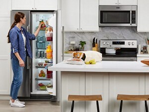 A woman putting food inside her open, side-by-side refrigerator