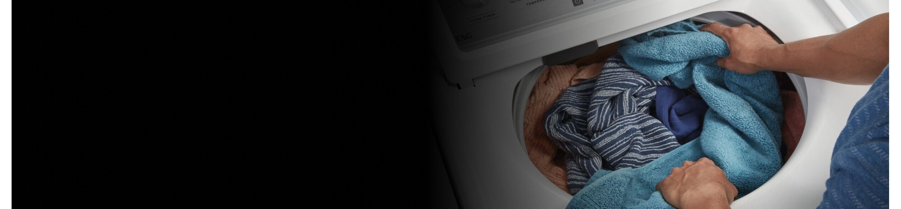 Person adding laundry to a washing machine