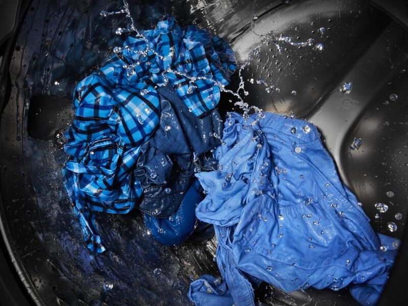 Blue clothing being cleaned in a washing machine