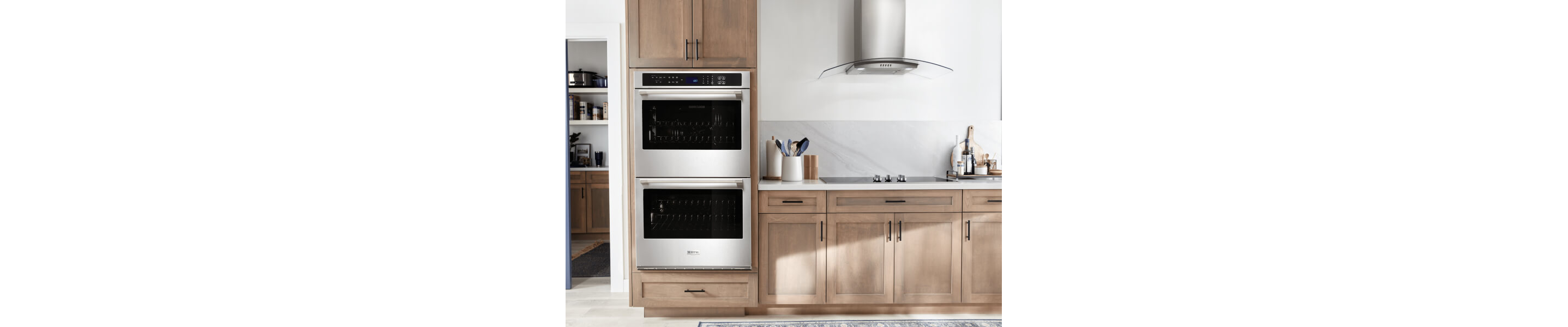 A Maytag® double wall oven, cooktop and range hood in a modern kitchen