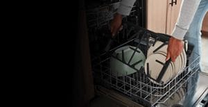 Person putting dishwasher-safe cast iron grates into the dishwasher