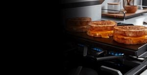Grilled cheese sandwiches cooking above an oval burner