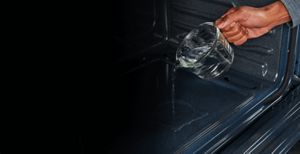 Person using water to steam clean their range oven