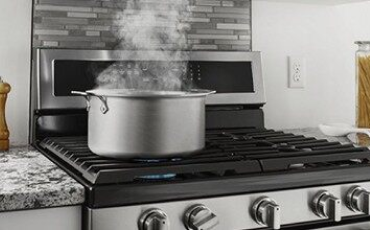 Pot of water boiling on a gas range.
