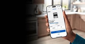 A hand holding a phone with the Maytag® Smart App open
