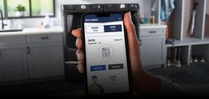 A hand holding a phone with the Maytag™ app screen