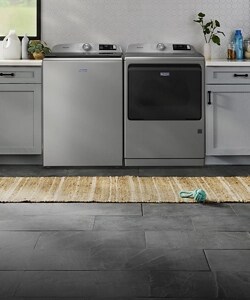 A top load laundry pair in a laundry room with pet toys laying around.