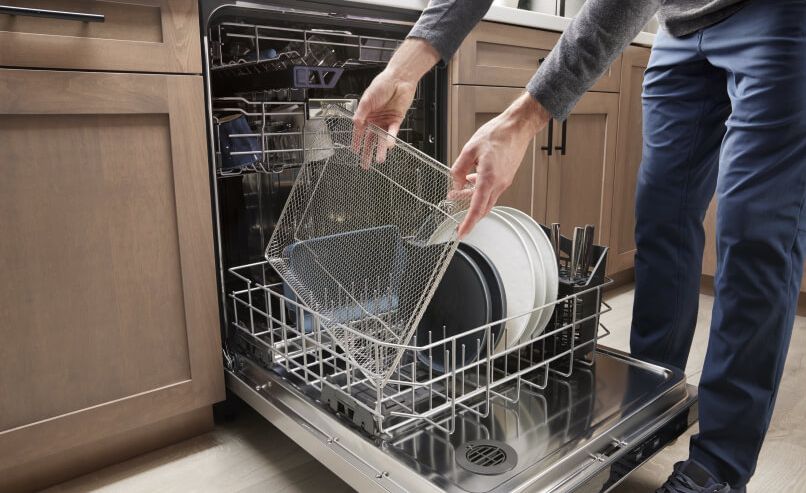 A person putting the air fry basket in a dishwasher.