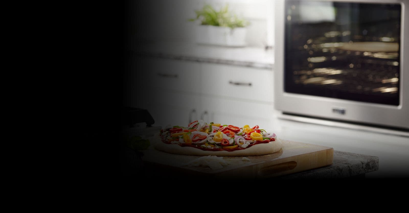 A flatbread pizza on a cutting board with a wall oven in the background.