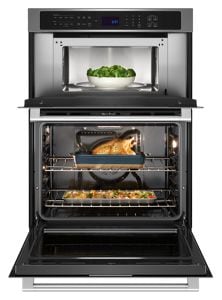 A stainless steel combination wall oven, open with food inside.