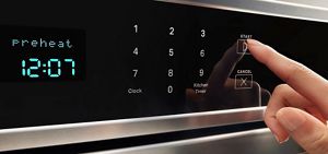 A finger pressing Start on a Maytag® wall oven control panel.