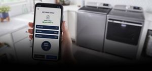 A hand holding a phone with the Maytag™ app screen
