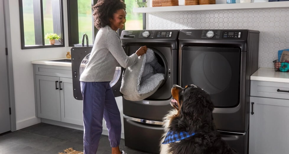A person putting laundry in a Maytag® washer.