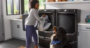 A person putting laundry in a Maytag® washer.