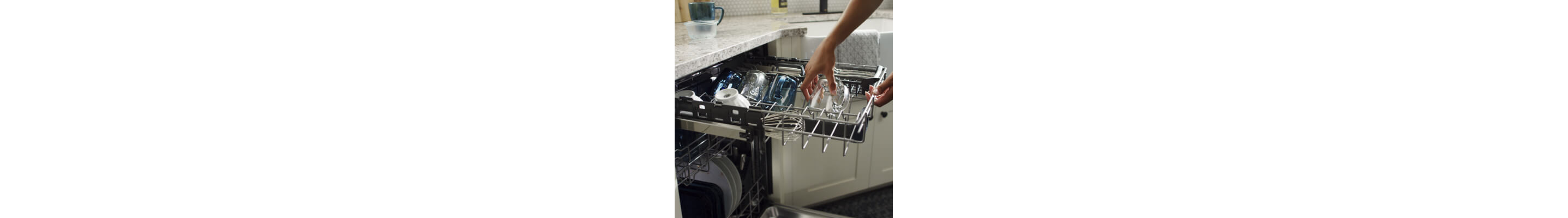 Person placing a glass mug in the top rack of a third rack dishwasher