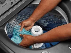 Someone rinsing a garment in the water stream of their washer