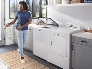 A person carrying a basket in their laundry room with a white washer and dryer set